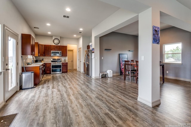 kitchen featuring visible vents, tasteful backsplash, wood finished floors, appliances with stainless steel finishes, and light countertops