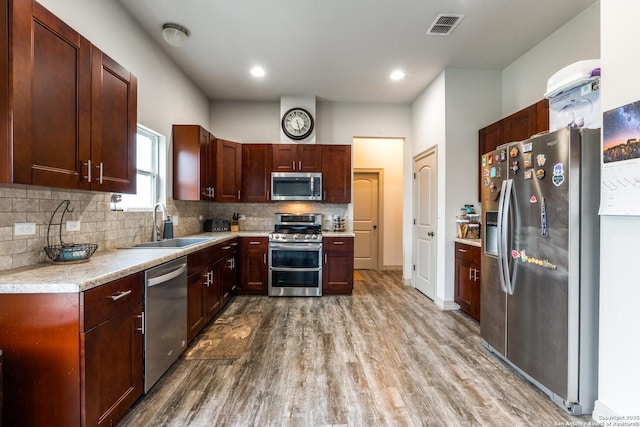 kitchen with visible vents, a sink, backsplash, wood finished floors, and appliances with stainless steel finishes