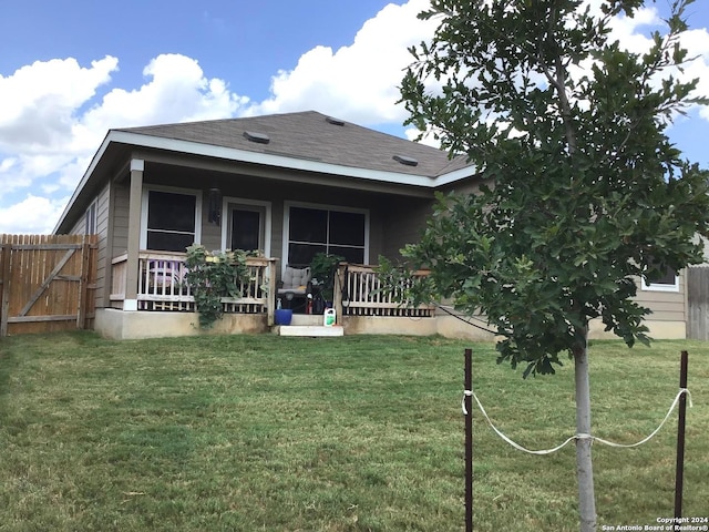 rear view of property featuring a lawn, a porch, roof with shingles, and fence