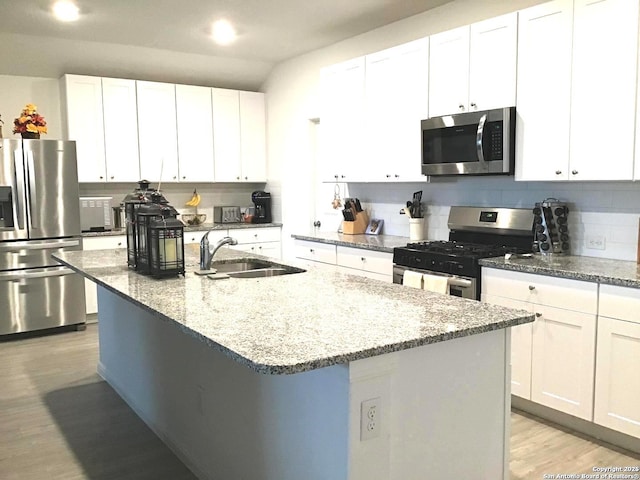 kitchen featuring light wood-type flooring, a sink, tasteful backsplash, white cabinetry, and stainless steel appliances