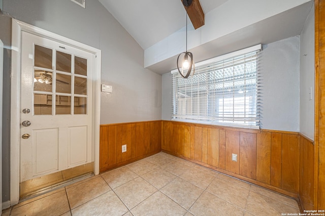 unfurnished dining area featuring light tile patterned floors, wainscoting, lofted ceiling with beams, and wood walls