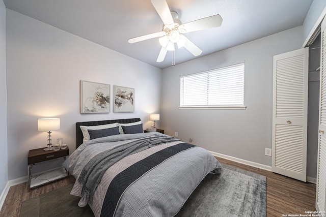 bedroom featuring a closet, baseboards, wood finished floors, and a ceiling fan