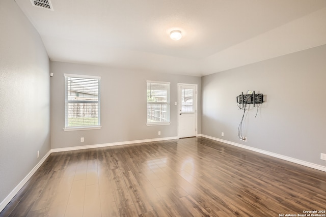 spare room featuring visible vents, baseboards, and dark wood-type flooring