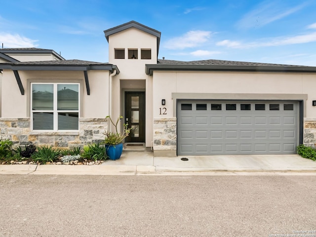 prairie-style home featuring stucco siding, stone siding, and concrete driveway