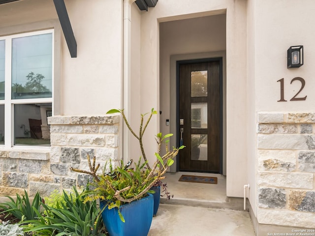 property entrance with stucco siding and stone siding