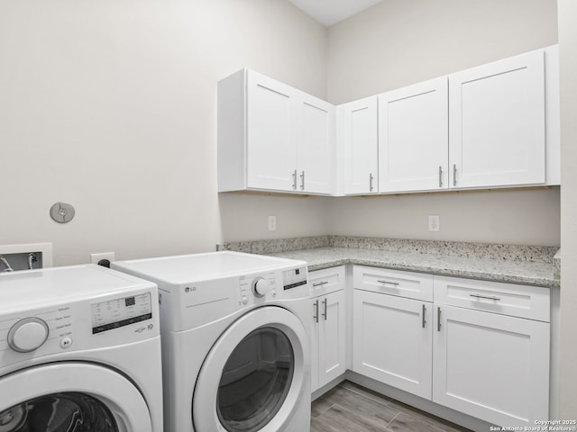 laundry room featuring cabinet space, washing machine and dryer, and light wood finished floors