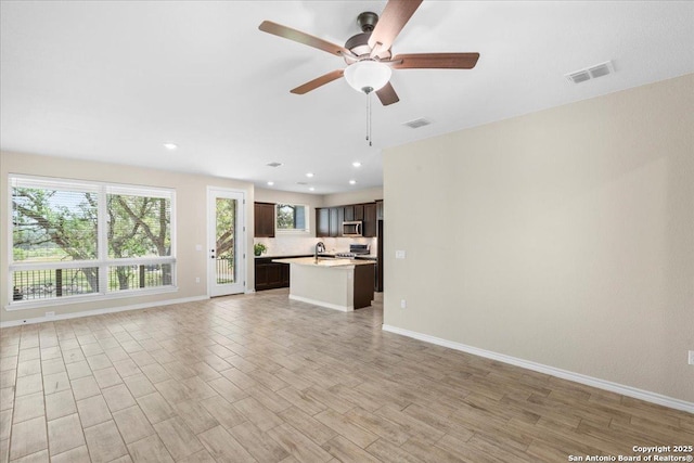 unfurnished living room featuring a sink, visible vents, light wood-type flooring, and baseboards