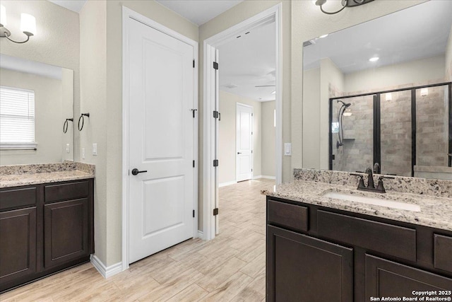 bathroom with a shower stall, vanity, baseboards, and wood finished floors