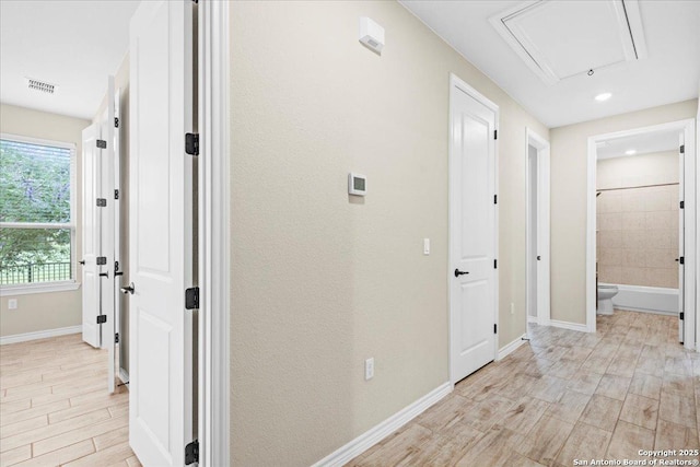 hallway featuring visible vents, baseboards, and wood finish floors