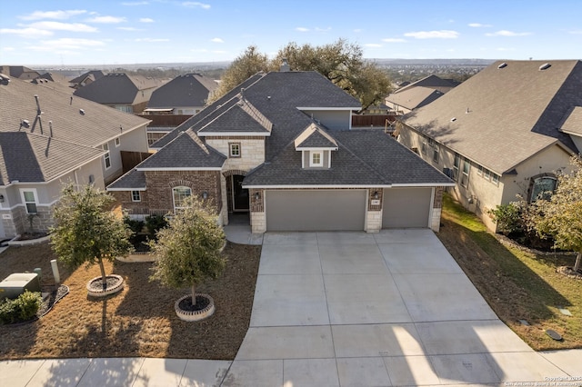 view of front of property with driveway, a residential view, stone siding, and roof with shingles