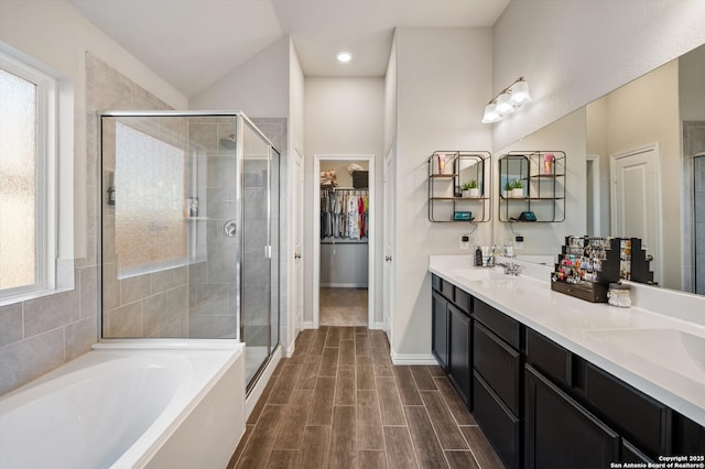 full bathroom with a walk in closet, wood tiled floor, a bath, and a shower stall