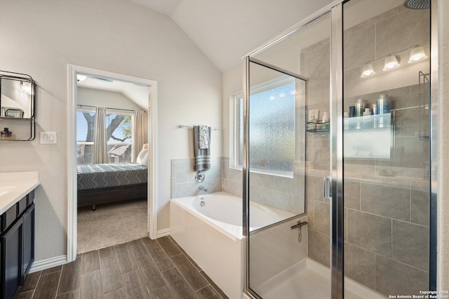 full bath with wood finish floors, ensuite bathroom, a shower stall, vanity, and vaulted ceiling