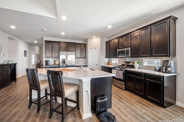 kitchen with stainless steel appliances, dark brown cabinets, a breakfast bar area, and wood tiled floor