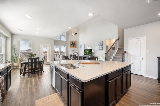 kitchen featuring vaulted ceiling, wood finished floors, dark brown cabinetry, and a sink