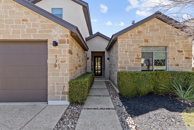 view of exterior entry with an attached garage, stone siding, and stucco siding