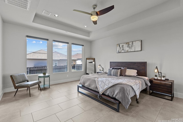 bedroom with a tray ceiling, light tile patterned floors, baseboards, and visible vents