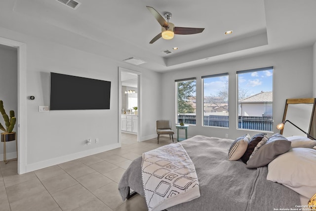 bedroom with light tile patterned flooring, visible vents, baseboards, and a tray ceiling