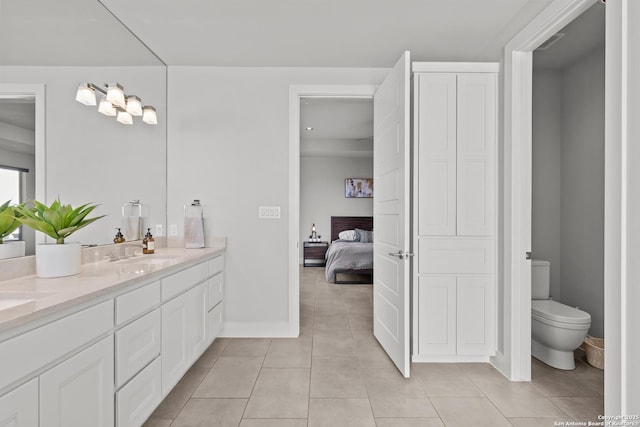 bathroom featuring toilet, ensuite bathroom, a sink, tile patterned flooring, and double vanity