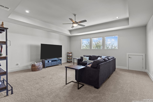 carpeted living room featuring a tray ceiling, baseboards, and visible vents