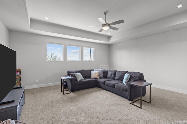 living room featuring carpet flooring, ceiling fan, baseboards, and a tray ceiling