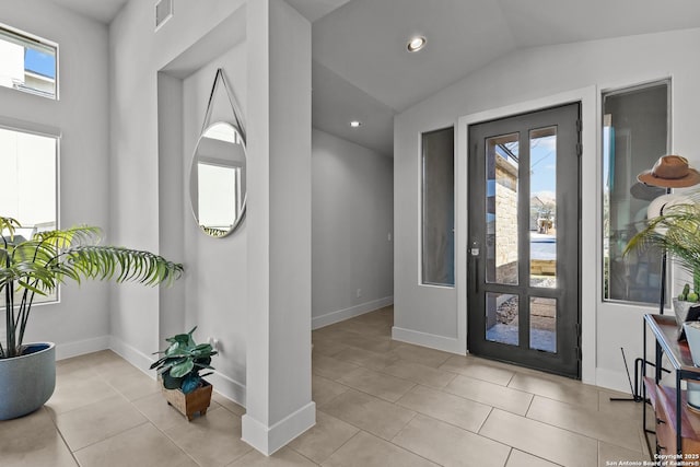 foyer featuring a wealth of natural light, visible vents, light tile patterned floors, and vaulted ceiling