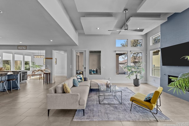 living room featuring a ceiling fan, wine cooler, a healthy amount of sunlight, and a large fireplace