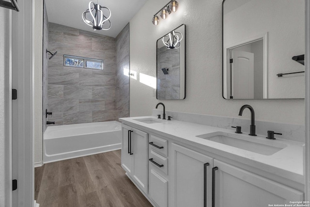 bathroom featuring double vanity, wood finished floors, shower / bathing tub combination, and a sink