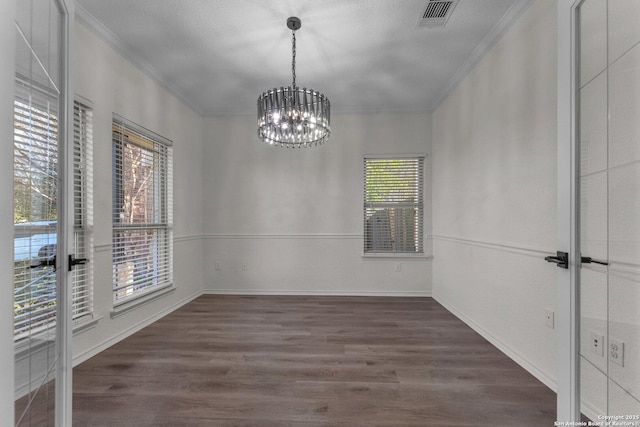 unfurnished dining area with visible vents, an inviting chandelier, wood finished floors, and crown molding