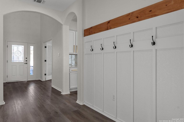 mudroom with dark wood-style floors, visible vents, arched walkways, and baseboards