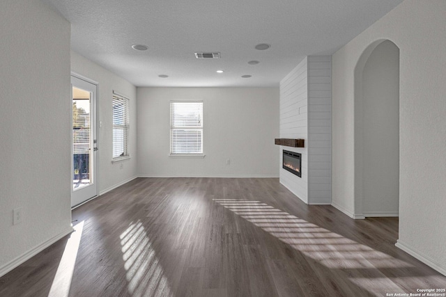 unfurnished living room featuring visible vents, baseboards, wood finished floors, and a fireplace