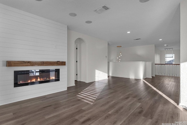 unfurnished living room with visible vents, recessed lighting, wood finished floors, arched walkways, and a glass covered fireplace