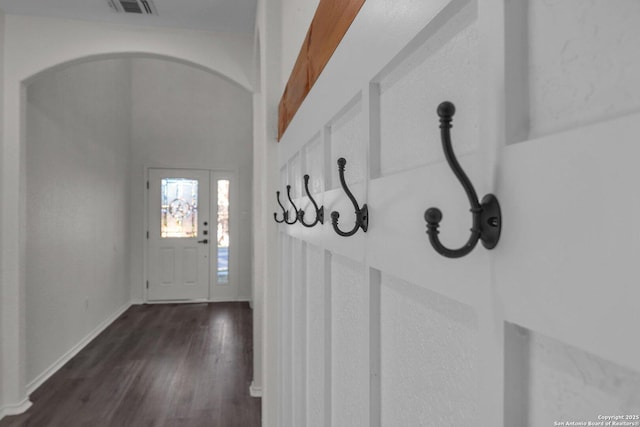 interior space featuring arched walkways, visible vents, baseboards, and wood finished floors