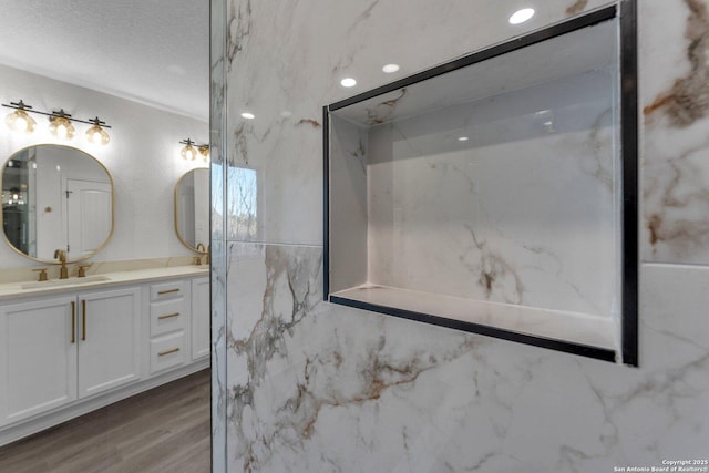 bathroom with a textured ceiling, vanity, and wood finished floors