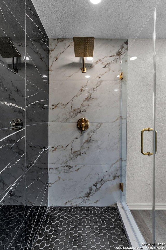 full bath featuring a marble finish shower and a textured ceiling