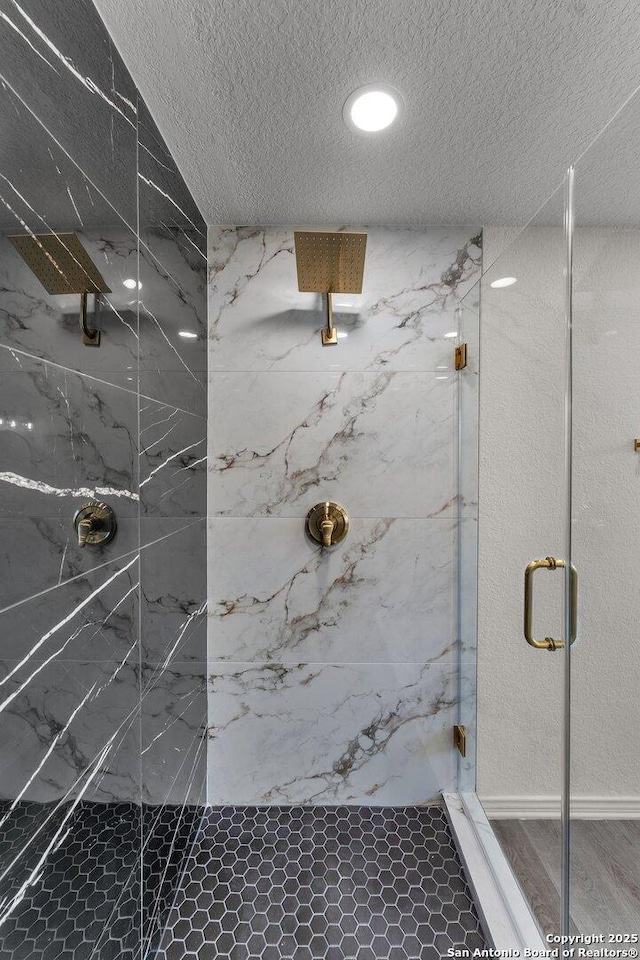 full bath featuring a marble finish shower and a textured ceiling