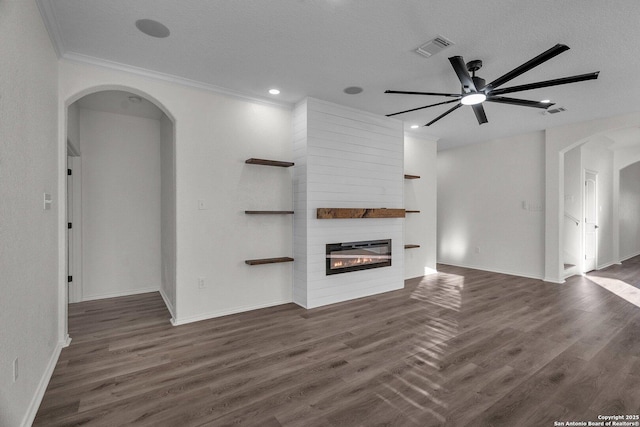 unfurnished living room with wood finished floors, visible vents, arched walkways, and a large fireplace