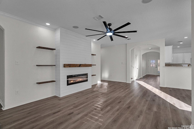 unfurnished living room featuring visible vents, a fireplace, wood finished floors, arched walkways, and a textured ceiling