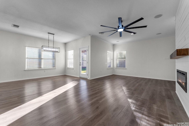 unfurnished living room featuring visible vents, a large fireplace, dark wood finished floors, a textured ceiling, and a ceiling fan