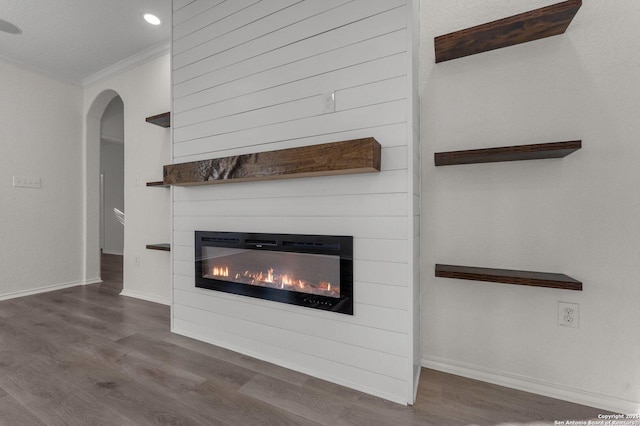 details with wood finished floors, baseboards, a fireplace, arched walkways, and crown molding