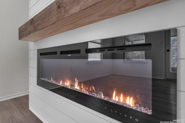 interior details with wood finished floors, baseboards, and a lit fireplace