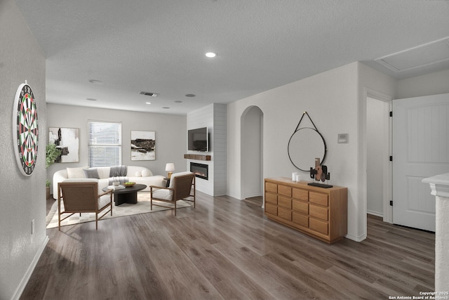 living area featuring wood finished floors, a fireplace, visible vents, and a textured ceiling