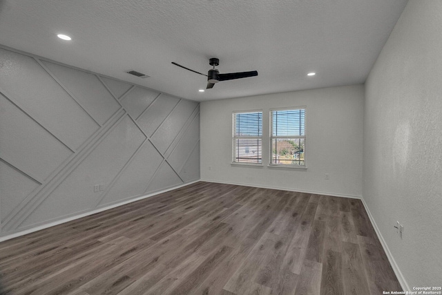 unfurnished room featuring baseboards, wood finished floors, visible vents, and ceiling fan