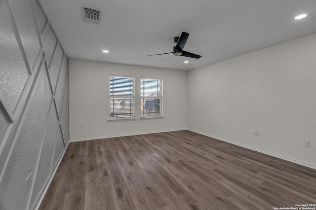 unfurnished room featuring baseboards, wood finished floors, visible vents, and ceiling fan