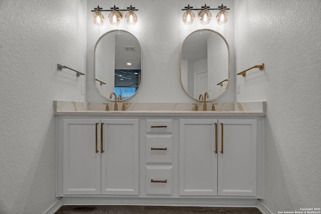 bathroom with a sink, double vanity, and a textured wall