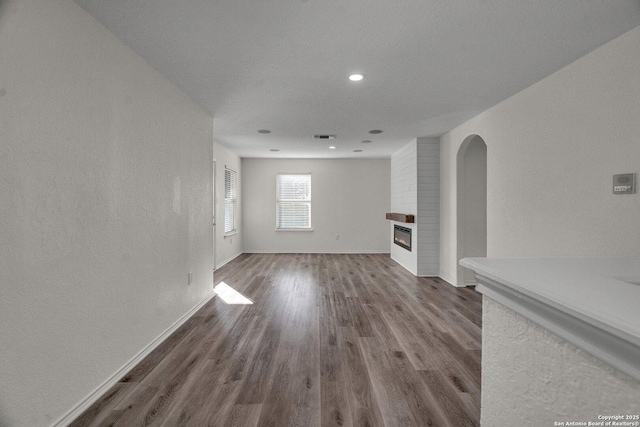 unfurnished living room featuring visible vents, a fireplace, baseboards, and wood finished floors