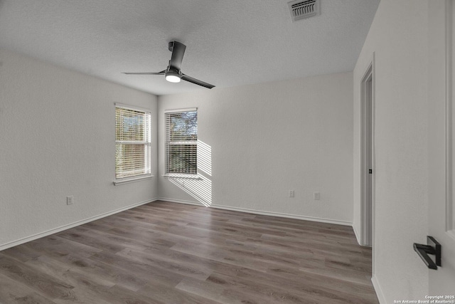 unfurnished room with visible vents, baseboards, ceiling fan, wood finished floors, and a textured ceiling