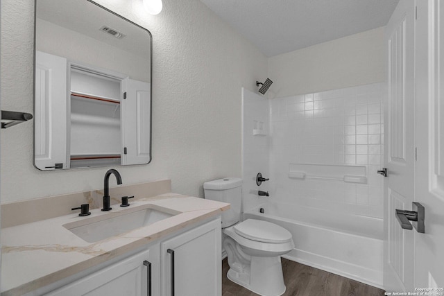 bathroom featuring visible vents, toilet, wood finished floors, shower / bathing tub combination, and vanity