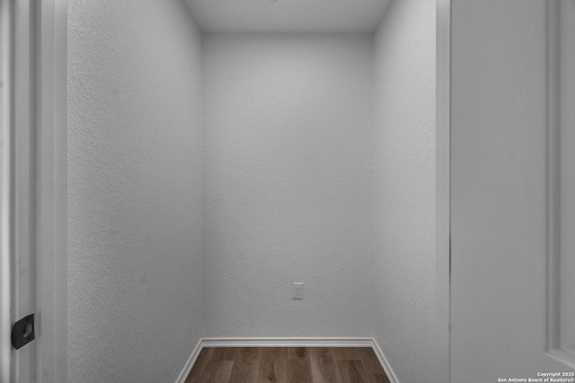 interior space featuring wood finished floors, baseboards, and a textured wall