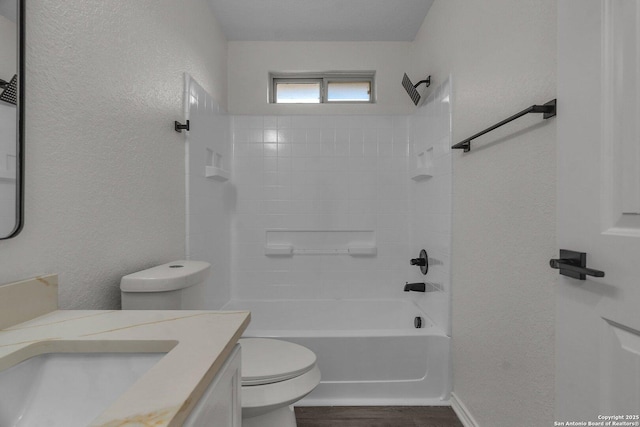 full bath featuring toilet, wood finished floors, vanity, shower / bathtub combination, and a textured wall