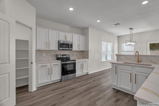 kitchen with visible vents, dark wood finished floors, a sink, appliances with stainless steel finishes, and white cabinetry